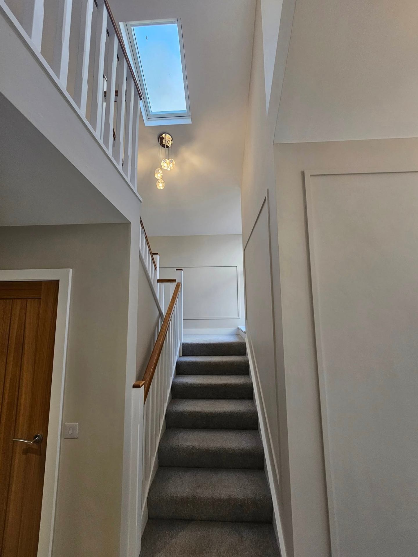 Stairwell with high ceiling, fresh white paint and oak handrail in Cardiff